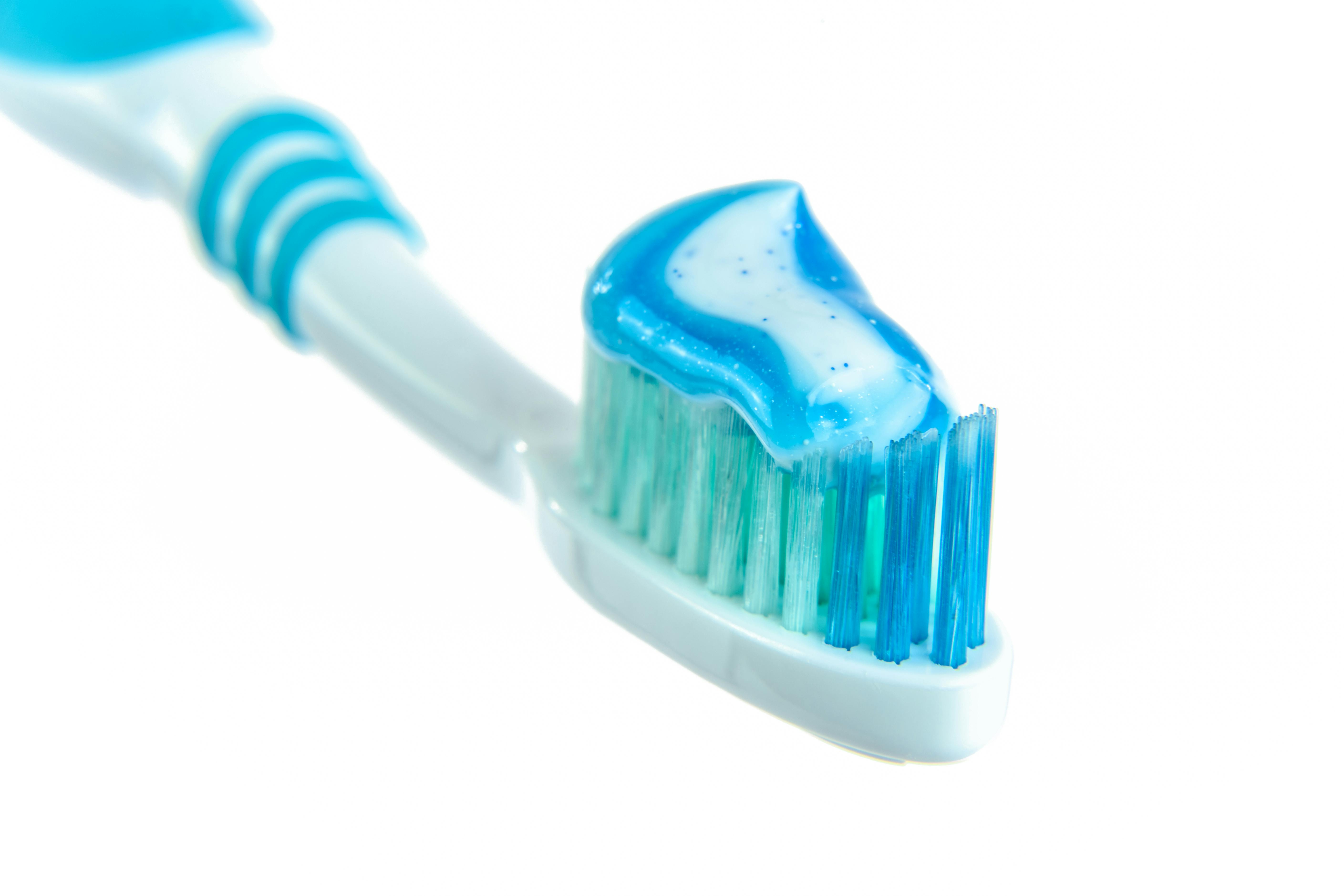Detailed close-up image of a toothbrush with vibrant blue toothpaste for dental hygiene.