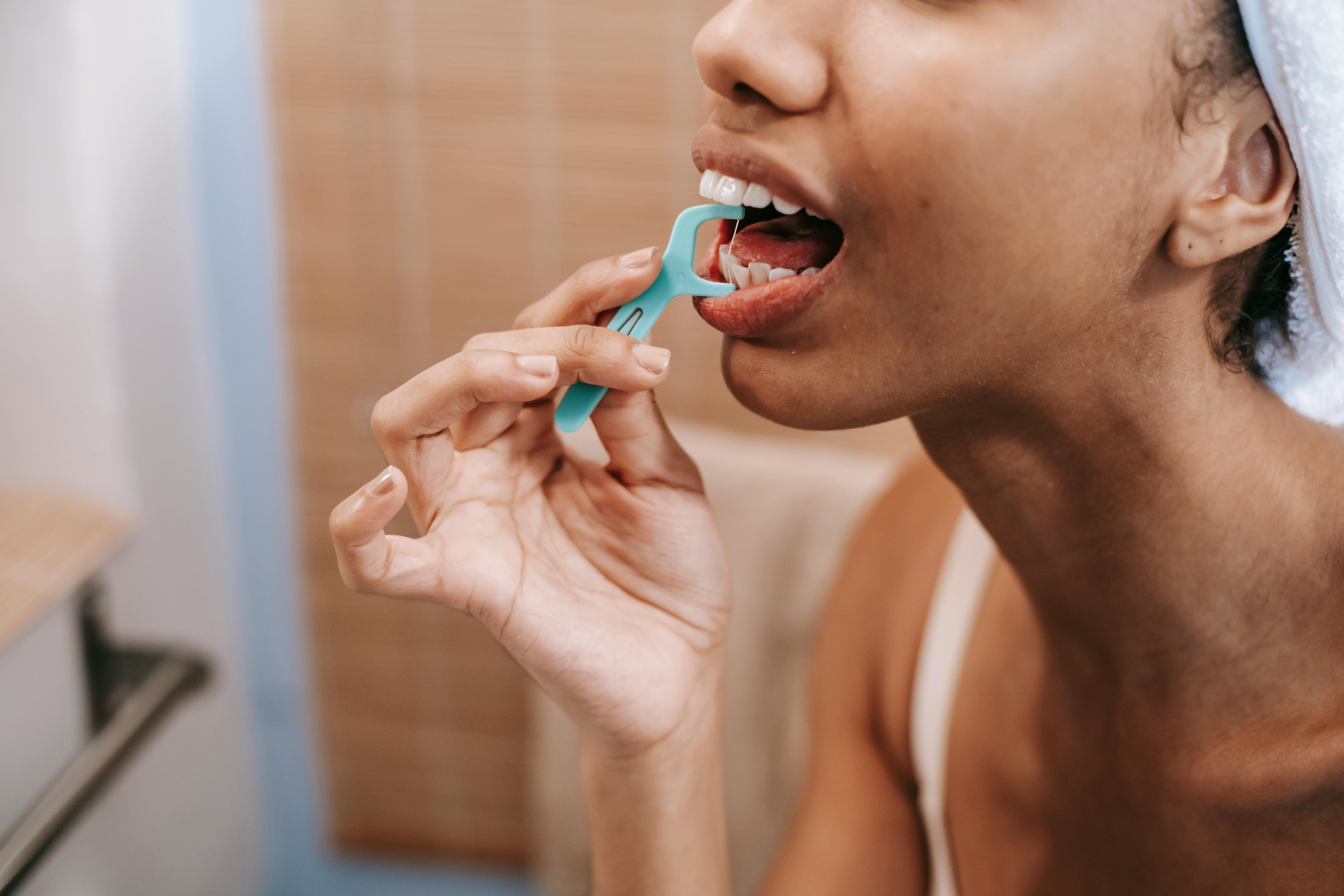 Close-up of a woman using a dental floss pick, promoting oral hygiene and daily care.